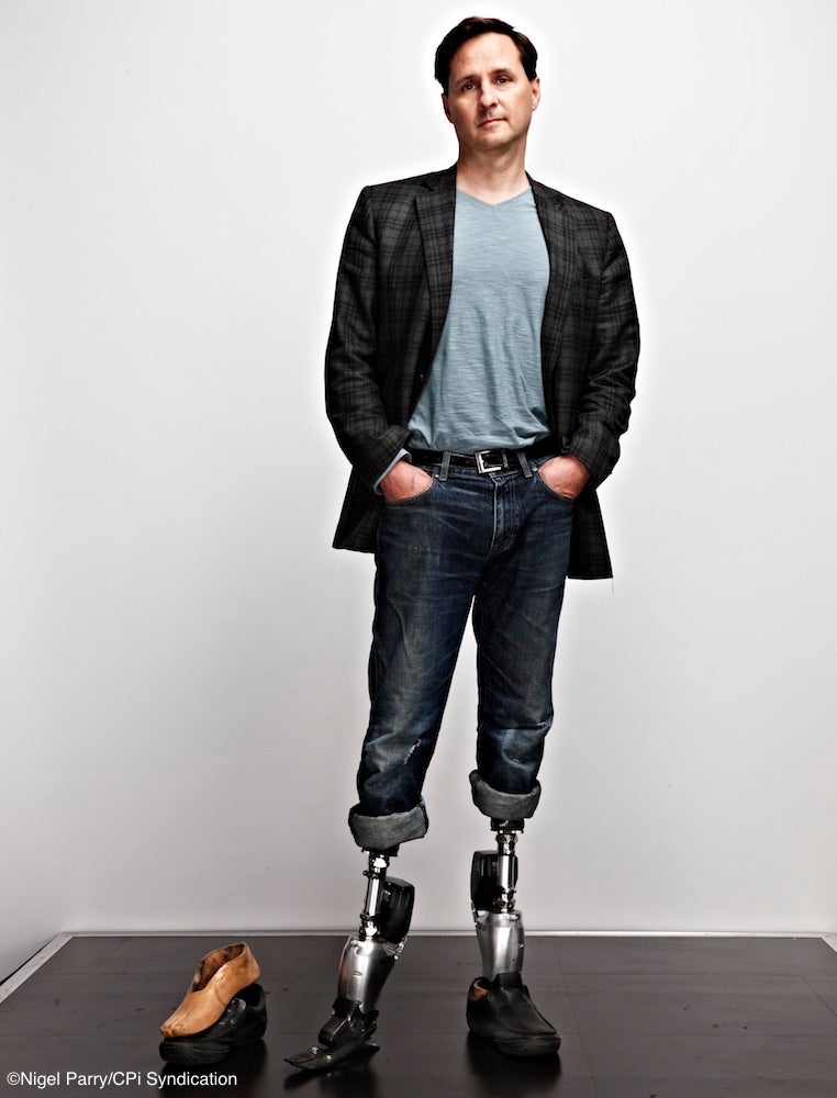 Hugh Herr posing in a suit with prosthetic legs
