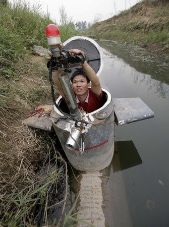 A Chinese man inside a homemade submarine made out of oil barrels.