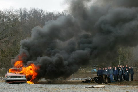 Students watch a car burn that was set on fire at a forensic training school in Tennessee. They were trying to determine what fluid was used to start the fire.