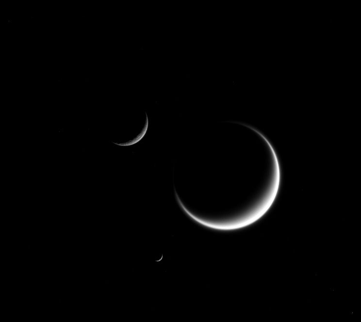 Saturn has 53 moons that have been named and another nine that are being studied. Cassini-Huygens, an unmanned spacecraft captured an image of three of those many moons using its narrow-angle camera. Titan is the largest moon in the image and appears fuzzy due to its cloud layers. Rhea is on the upper left, and the one on the bottom is Mimas.