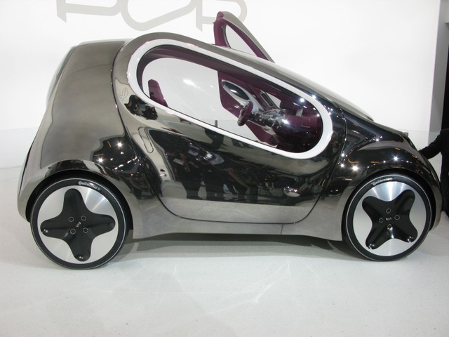 The 10-foot-long 3-seater with oblong diagonal side windows and claw-like headlights is a fully electric, zero-emissions vehicle that runs on lithium polymer batteries. Six-hour charge, 80 mile-an-hour top speed, and 100 miles on a charge.