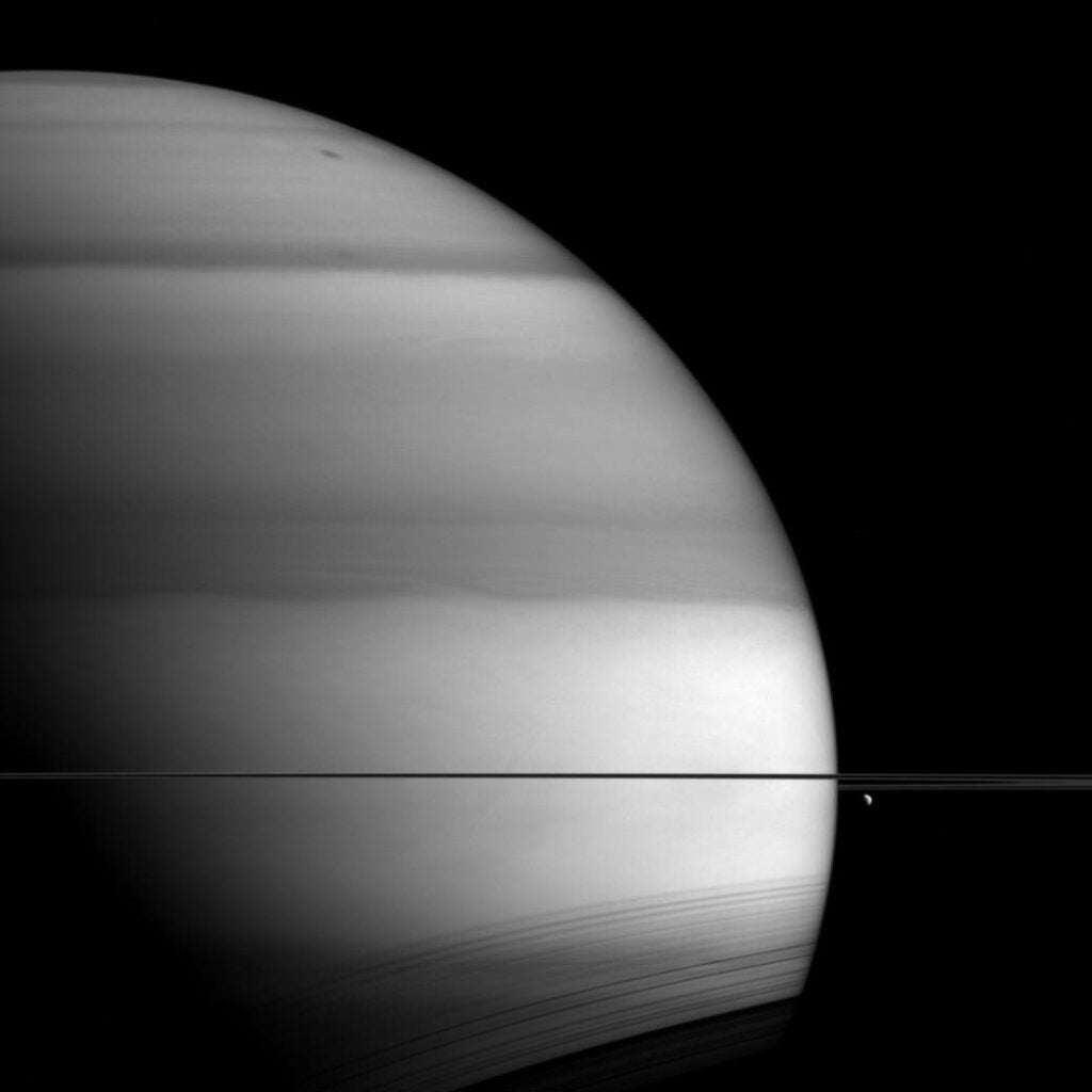 Saturn is flanked by moon Dione in this photo, hanging just below its rings to the right. The bands appearing to pattern the planet are from the methane in its atmosphere, according to <a href="http://www.nasa.gov/image-feature/jpl/pia18354/methane-saturn">NASA</a>.