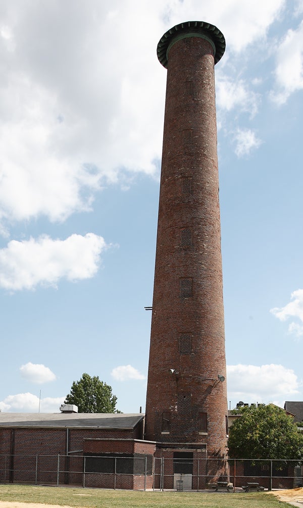 A several-story-tall cylindrical brick tower next to a one-story brick building.