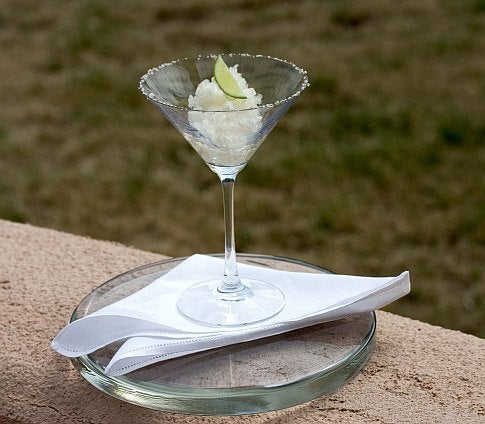 A citrus granita margarita in a glass on a plate outside.