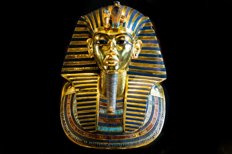 The famous burial mask of King Tutankhamun on display at the Egyptian Museum in Cairo, Egypt. The 24 pound (11 kilogram) mask is made of gold, glass, and precious stones. The nemes headdress features a vulture, symbolizing sovereignty over Upper Egypt, and a cobra, symbolizing sovereignty over Lower Egypt.