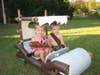 Two children sitting in a homemade Flintstones car, dressed as Pebbles and Bam-Bam.