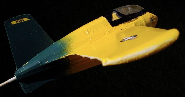 A yellow-and-green model plane against a black background.