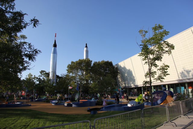 The New York Hall of Science is a great choice of venue--its rockets are visible to anyone riding the 7 train out to Queens, and it was the site of both iconic New York City World's Fairs.