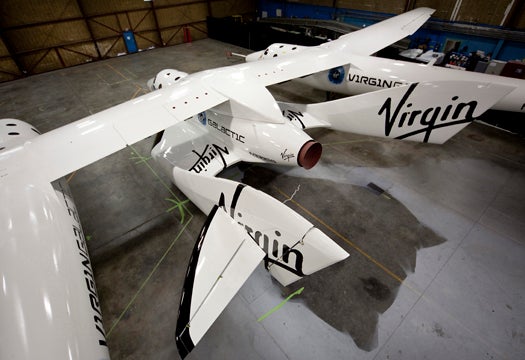  SpaceShipTwo resting under the Mothership WhiteKnight2 inside a hangar in Mojave,Ca. SpaceShipTwo will have its worldwide debut Monday evening at the Mojave airport for dignitaries and future "astronauts".