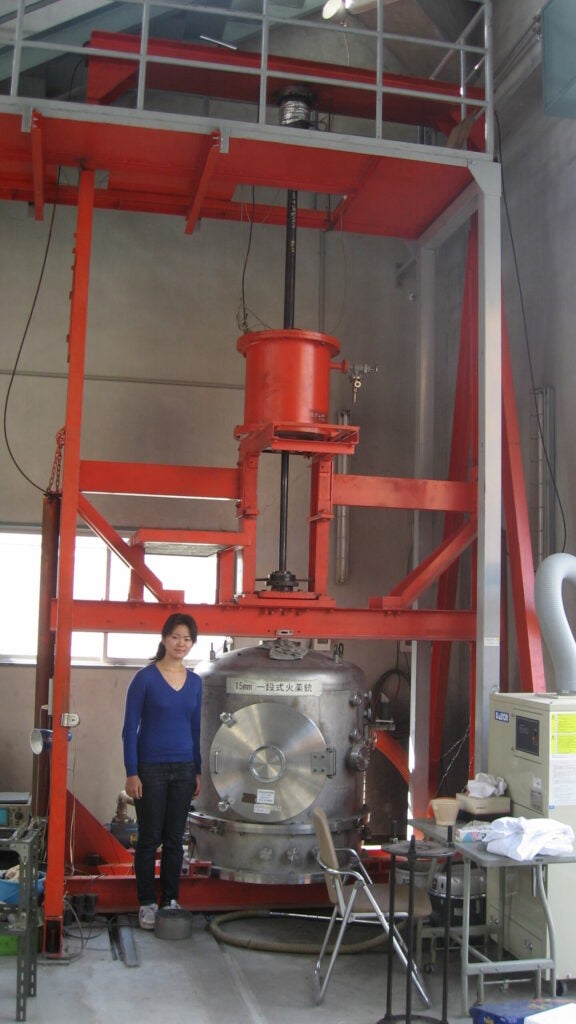 Haruna Sugahara, lead author of the study, stands next to a vertical propellant gun.