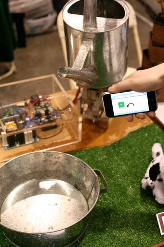 A person using an iPhone to control a watering can at Maker Faire 2008 in San Francisco.