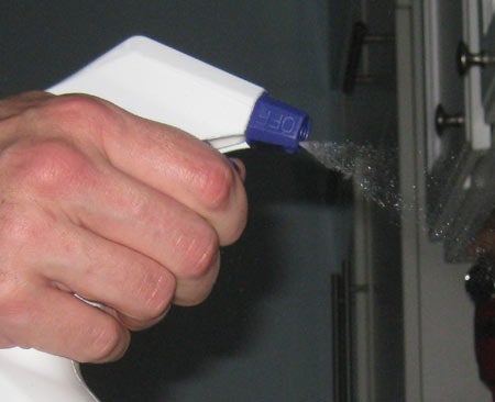 A person spraying liquid out of a spray bottle.