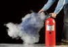A person spraying a fire extinguisher into a pillowcase against a black background.