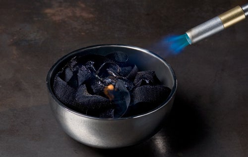 Velcro in a small metal pot, burning in air.