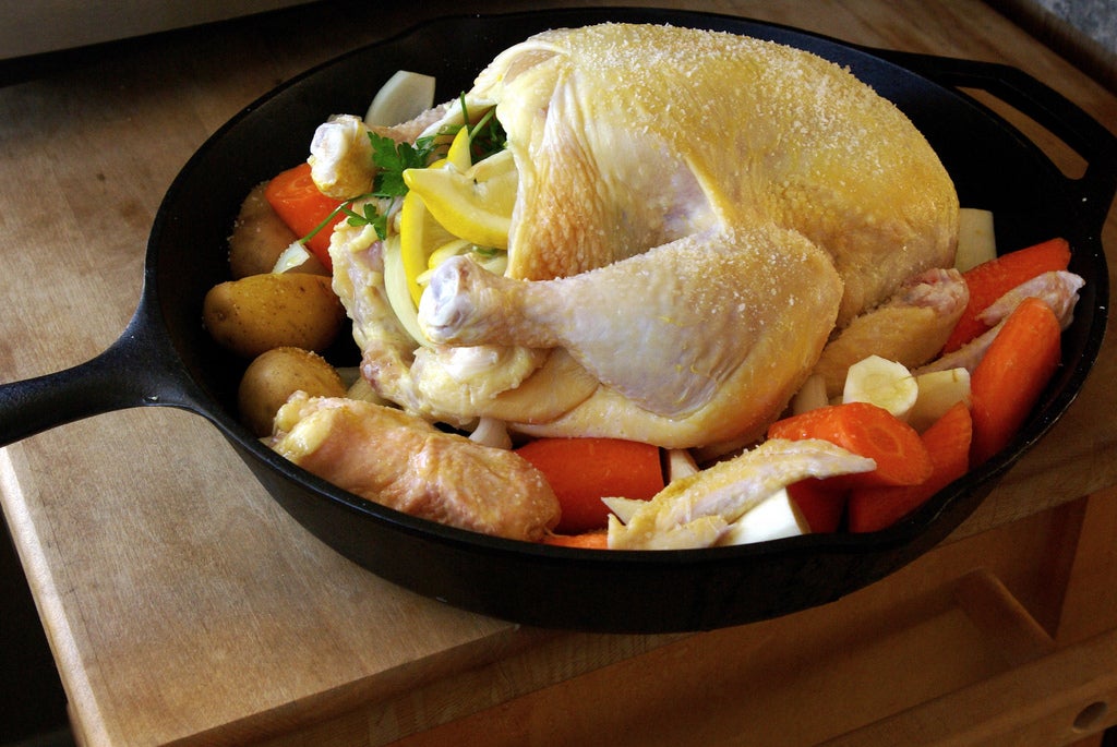 cooking a whole chicken with veggies on a skillet