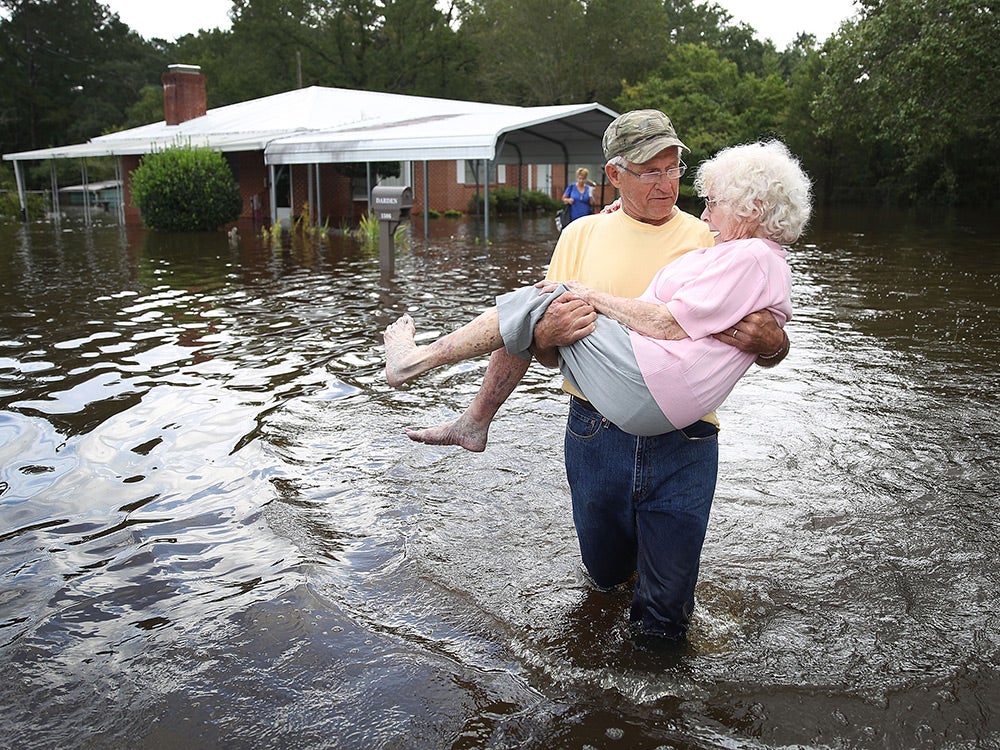 elderly man carrying wife through flood