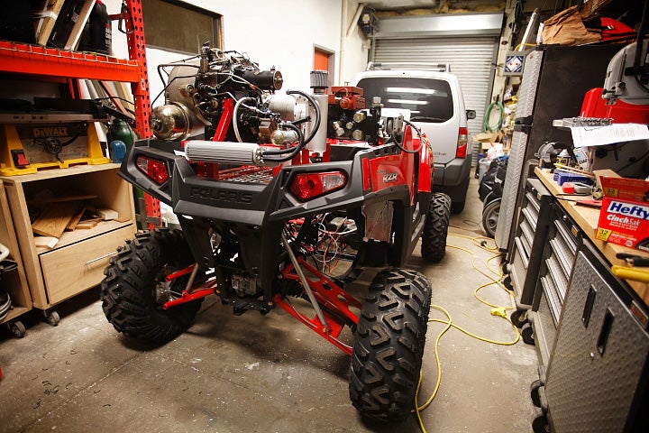 A red ATV in a garage with its cage removed.