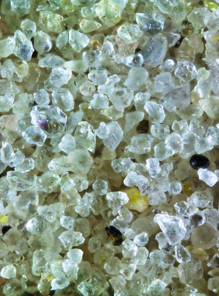 This sand from Hilton Head, South Carolina on the Atlantic is mostly quartz and it originated in the Appalachian Mountains. A sand comprised almost entirely of quartz, like this one, is indicative of sand originating on a continent where the ancient bedrock is granite. Granite is composed of quartz, feldspar, and other dark minerals. As it erodes, the feldspar breaks down into clay-size particles and the hard and chemically stable quartz survives to become grains of beach sand. Magnified 60 times.