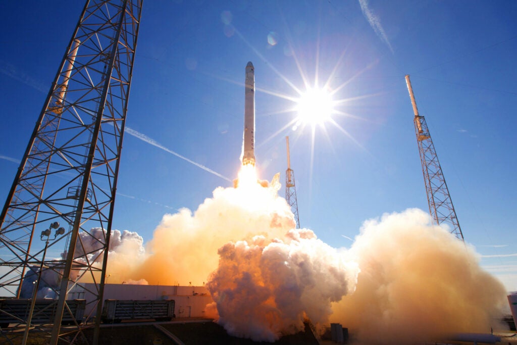 SpaceX Falcon and Dragon lift off from their launch pad on a sunny day