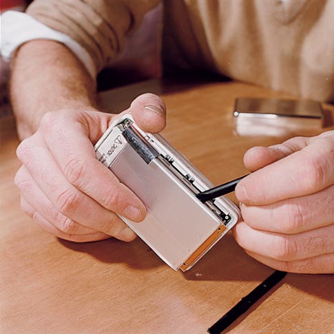 <em>With the case off, use the same tool to gently pry the battery (left) from the hard drive.</em>