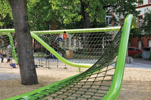 To create an undulating climbing space that meanders through the trees, designers erected two green steel pipes with a net strung between. In some sections, traversing the structure can involve swinging from ropes with rotating plates.