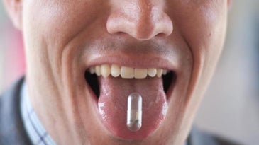 Christopher Bettinger displaying an edible battery made with melanin and dissolvable materials on his tongue.