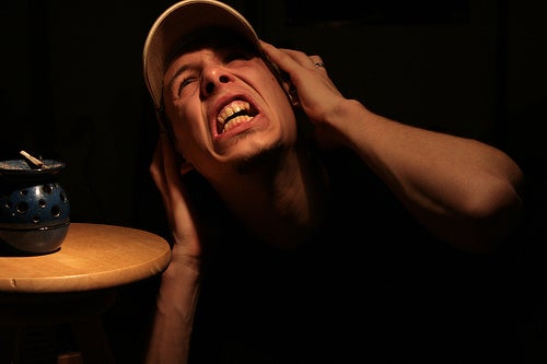 a man covering his ears with a pained look on his face