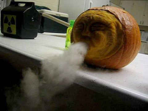 A carved pumpkin blowing a cloud of smoke out of its mouth.