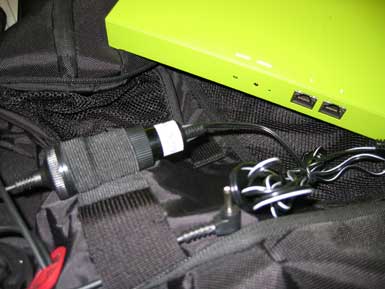 A chartreuse power bank with wires in a black backpack.