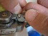 A person attaching a metal bracket to a small motor with screws.