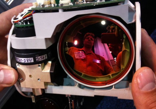 Rob Gilchrist, a mechanical engineer with Goodrich, shows off a new lightweight surveillance gimbal fitted with an electro optical camera and an incredibly compact infrared camera. The seven-pound T3 illustrates the effort to pack ever more functionality into smaller payloads, thus extending flight time.