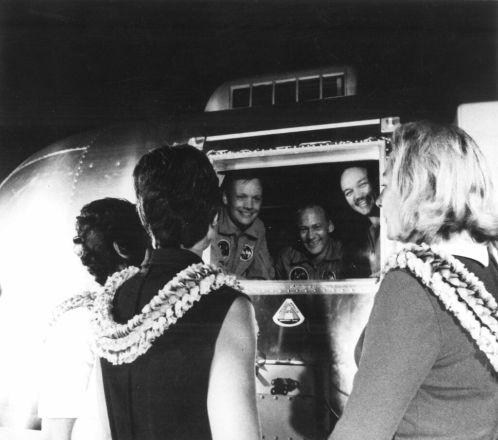 Three days after splashdown, still in quarantine at Ellington Air Force Base, the crew of Apollo 11 greets their wives.