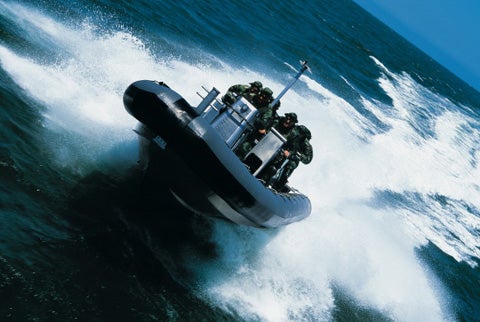 A Zodiac 870 boat photographed off of Norfolk, VA with former Navy SEALs from a Bell Jet Ranger helicopter, flying sideways very low to the water.
