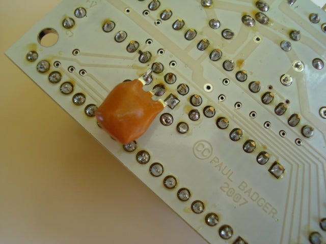 A ceramic resonater soldered to a printed circuit board.