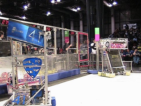 Two homemade robots in an arena in front of a crowd at the 2009 FIRST Robotics Competition in New York City.