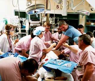 ALL HANDS<br />
Crises in the trauma bay play out like a frenetically choreographed modern dance. Here, Dr. Alan Heins performs CPR on a patient in full arrest, while looking to trauma attending physician Jeff Johnson (right, foreground) for guidance.