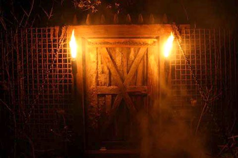 A homemade drawbridge with torches on either side, at night.