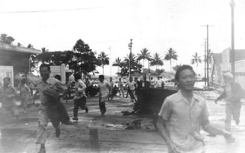 People run from the approaching tsunami. Note the wave just left of the man's head in the right center of the image.
