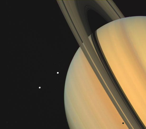 Voyager 1 photographed Saturn and two of its moons, Tethys (shown here) and Dione in November 1980. Shadows from Saturn's three bright rings and Tethys can be seen on the cloud tops on Saturn.