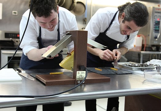 After the raclette grill has done its job, Sam Fahey-Burke and Max Bilet assemble the cheese course.