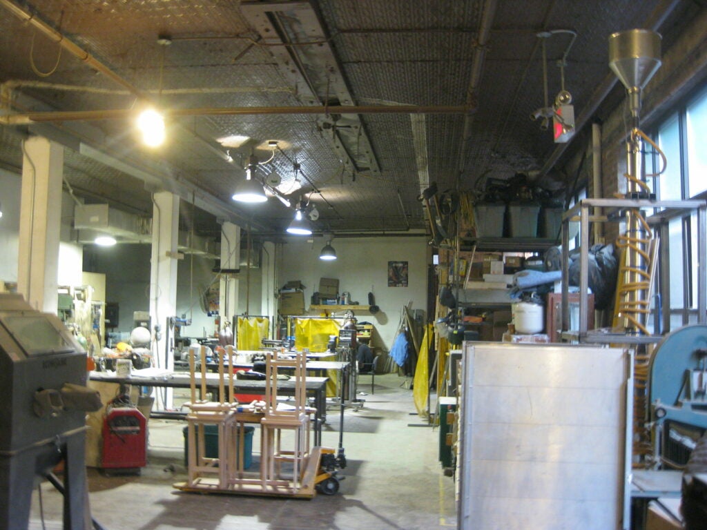The pyrolyzer (at right, with the funnel-shaped hopper on top) sits in the wood and metal shop at 3rd Ward.