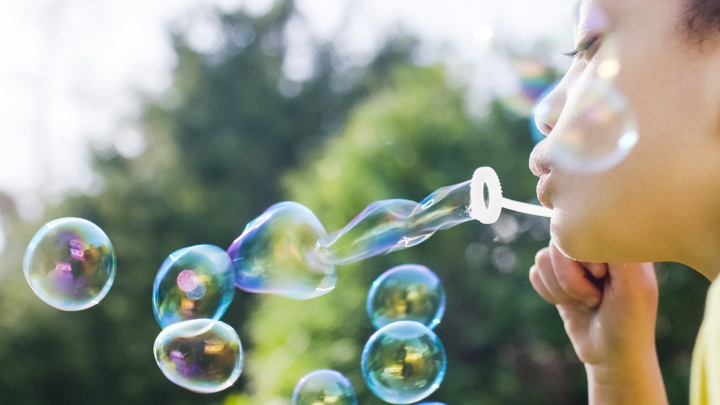 a girl blowing bubbles outside