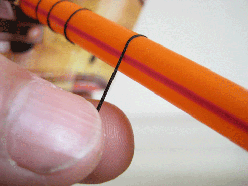A person using very thin electrical tape to make lines on a straw.