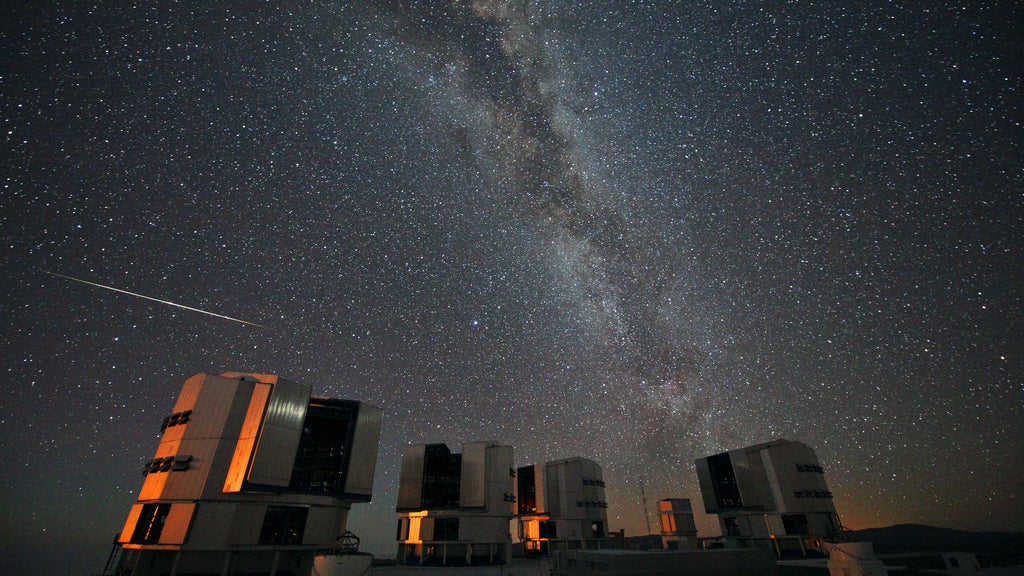 starry night sky above telescopes on hill 