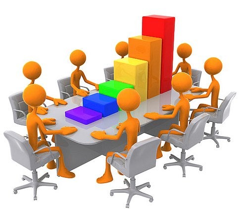 Eight orange stick figures sitting around a conference room table with a bar chart on top of it.