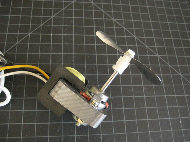 A motor with a propeller on it, on top of black grid paper.