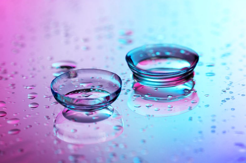 two contact lenses on a pink and blue background