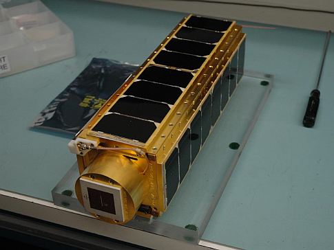 The satellite payload sits fully assembled, covered in shiny solar panels.