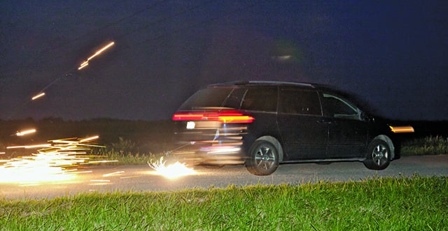 A minivan dragging a block of Mischmetal (German for "mixed metal") along a road at night, creating many sparks.
