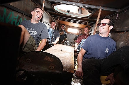 A group of men laughing as they pedal inside a replica tank.